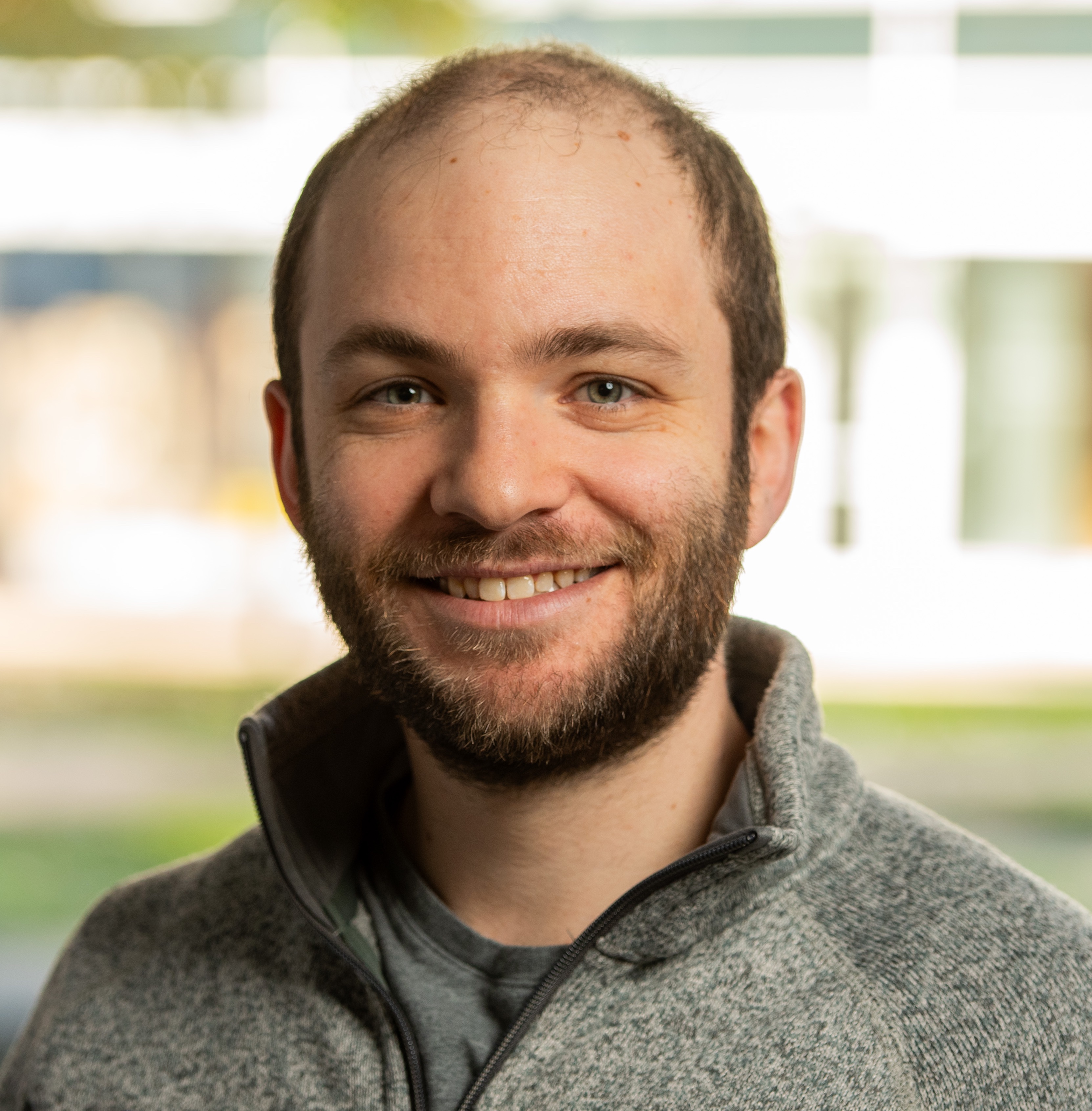 A brunette man with a beard smiling