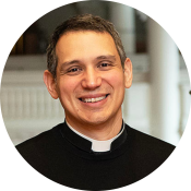 Reverand Matthew Potts, a white man wearing a priest's collar, smiling